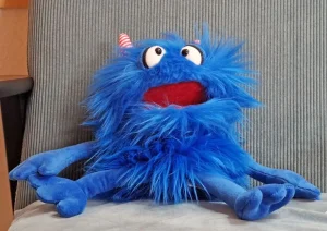 Ein blaues Plüschtier sitzt im Sessel