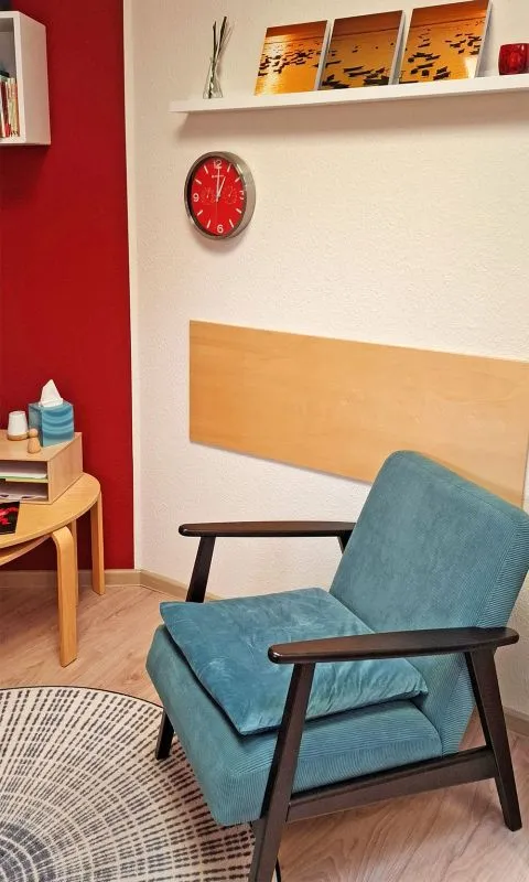 Blauer Sessel im Behandlungszimmer mit kleinem runden Tisch